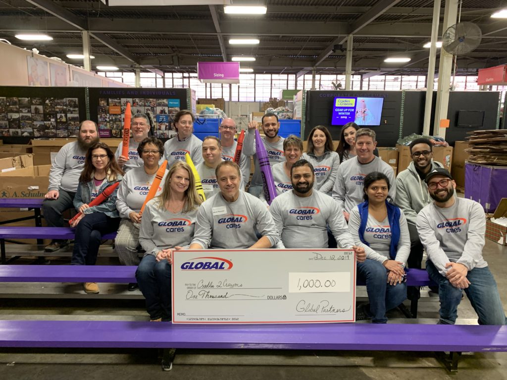 Global Employees present a giant check at the Cradles to Crayons event.