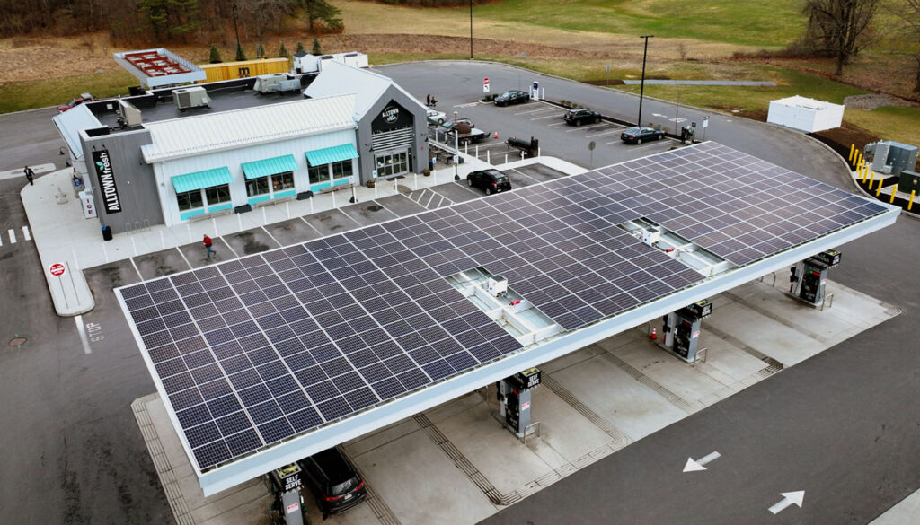 Aerial shot of a solar array over a charging station in a convenience store parking lot.