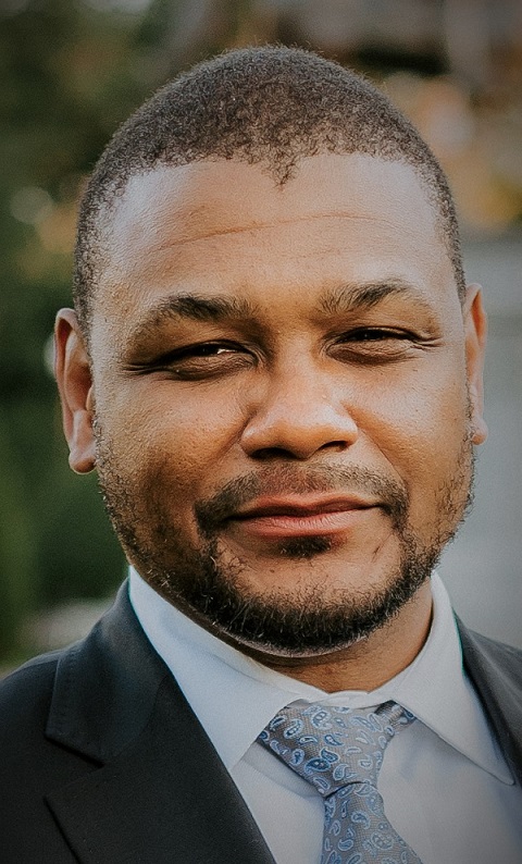 Person wearing dark blazer over white collared shirt with light colored tie.